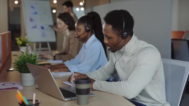 Afroamerikaner in Kopfhörer mit Laptop im Callcenter — Stockvideo