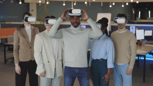 Équipe multiraciale posant dans un casque VR dans un bureau moderne — Video