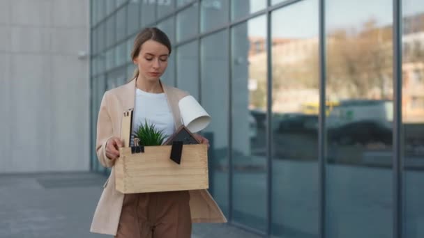 Bir kutu eşya ile modern iş merkezinin yakınında yürüyen bir kadın. — Stok video
