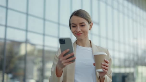 Frau mit Kaffee steht draußen und benutzt Handy — Stockvideo