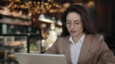 Modern laptopla kafede oturan göz zevkli bir kadın.