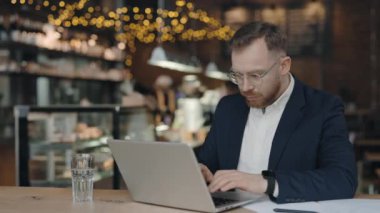 Yorgun işadamı mali belgeleri kontrol ederken kaşlarını çattı, koluyla sırtını sıvazladı, dizüstü bilgisayardaki modaya uygun kafede oturdu, istatistikleri analiz etti, aşırı çalıştı.