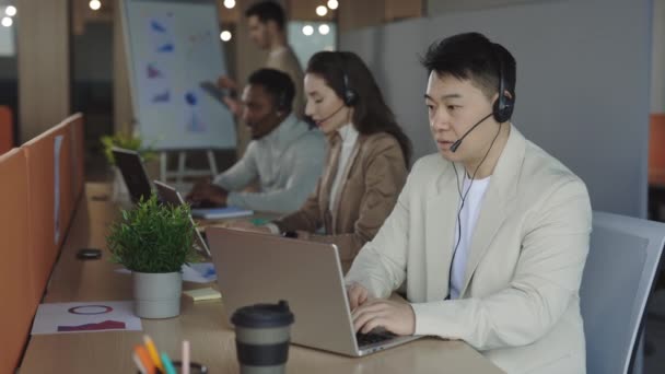 Asiatischer Männlicher Callcenter Agent Bindet Sich Einen Modernen Laptop Und — Stockvideo