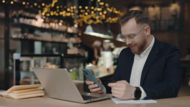 Cep telefonuna kredi kartı numarası yazan bir işadamı, online başvurulardan eşyalar alan, kafede otururken para transfer eden biri. Kredi kartı ve akıllı telefon erkeklerin elinde.
