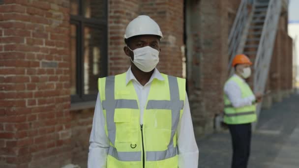 Yansıtıcı Üniformalı Koruyucu Maskeli Ciddi Bir Adam Tamamlanmamış Binanın Yakınında — Stok video