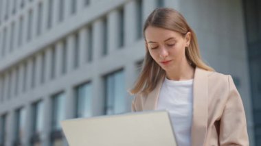 İş merkezinin yanında otururken dizüstü bilgisayarda daktilo kullanan, gündelik giyinen çekici bir kadın. Çevrimiçi çalışan çekici bayan ofis müdürü..