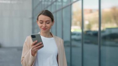 Kapalı saçlı çekici genç bir kadın dışarıda yürürken sesli mesaj kaydetmek için modern akıllı telefonu kullanıyor. İnsan kavramı, aygıtlar ve iletişim.