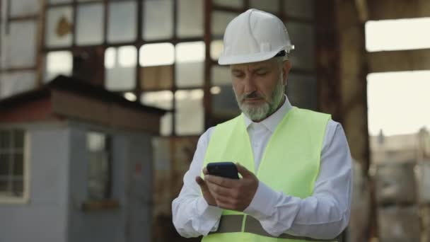 Focused Mature Foreman Reflective Vest White Helmet Using Cell Phone — Stock Video