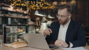 Ciddi bir iş adamı kafede görüntülü konferansta konuşuyor. Ceo dizüstü bilgisayarında görüntülü arama yapıyor. Uzak iş yerlerinde jestleri olan erkek profesyonel açıklama projesi