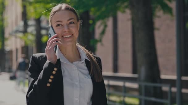 在办公中心附近的现代智能手机上 穿着时髦正装的快乐的女企业家们在聊天 积极的高加索女士在户外散步时谈论商业新闻 — 图库视频影像