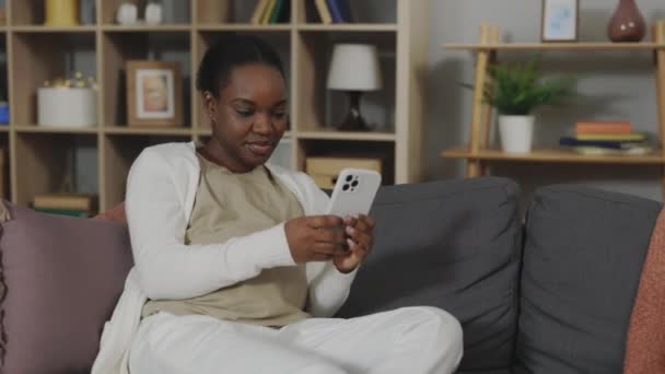 임신중인 아프리카 미국인 임산부가 소파에 불편하고 전화를 사용하는 있습니다 매력적 — 비디오