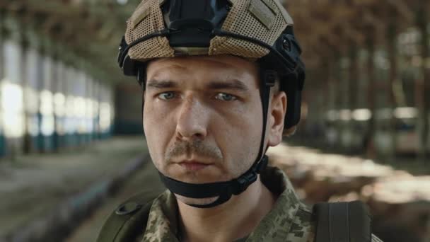 버려진 공장에서 카메라를 표정으로 바라보고 코카서스 군인의 방호용 헬멧을 군복을 — 비디오
