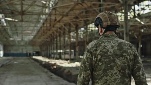 看到身穿军服 头戴安全帽 身披背包的强壮的美国战士在废弃的工厂中独自行走时的倒影 使命和勇敢的概念 — 图库视频影像