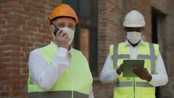 Ingeniero Caucásico Dando Tareas Por Walkie Talkie Los Trabajadores Mientras — Vídeos de Stock