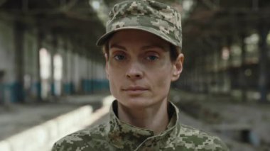 Gözlerinde yorgunluk olan kendine güvenen kadın memurun fabrikada durmuş dövüşürken kameraya bakışını kapatın. Savaş, ordu, ordu ve halk konsepti.