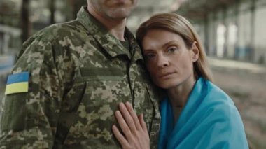 Mahvolmuş manufactory 'da sevgili kocasının kucağında kameraya bakan hoş, beyaz bir kadın. Kamuflaj üniformalı Ukraynalı erkek asker savaştan sonra geri dönüyor..