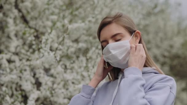 즐거움에 여자는 의료용 마스크를 자유를 느낀다 꽃피는 공원에서 날씨에 공기를 — 비디오
