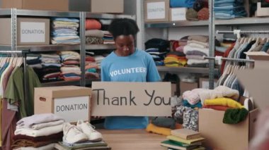 Çeşitli kadın gönüllülerin portre görüntüsü. Dolap afişi tutarken, teşekkür cümlesiyle ve gülümseyerek kameraya bakarken. Arkasında eşyalar olan raflar. İnsani yardım kavramı