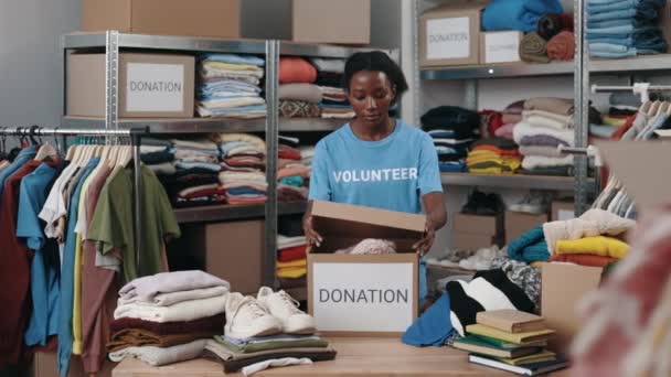 Brunette Woman Standing Warehouse While Sorting Iterating Clothes Donations Belongings — Vídeo de stock