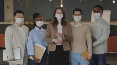 Portraits of business multicultural group standing at office with crossed arms wearing surgical masks in order to protect themselves from coronavirus. Health care concept