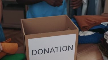 Çeşitli meslektaşlar bağış merkezinde çalışırken kıyafetlerini dolaba koyuyorlar. Gönüllüler ve insani yardım kavramı. Kırpılmış görünüm