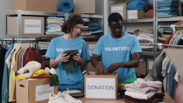 Voluntários Organizando Roupas Doadas Centro Comunitário Doação Caridade Trabalhadores Dobrando — Vídeo de Stock