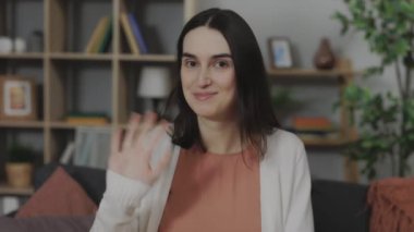 Webcam 'le konuşan mutlu beyaz kadın evinde kanepede oturup, el sallayarak hamilelik testi gösteriyor. Çekici esmer, olumlu sonuç veriyor.