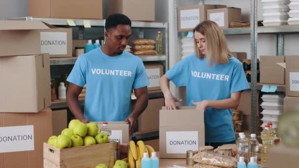Caucasian Woman African American Man Cooperating Together Food Bank Packing — Vídeos de Stock