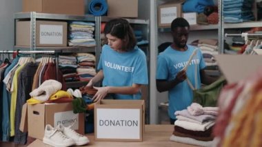Toplum bağış merkezinde bağışlanan kıyafetleri sıralayan çeşitli gönüllüler. İşçiler giysileri katlayıp depodaki dolaba koyuyorlar. İnsani yardım kavramı