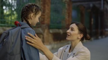 Anne okul saatinden önce okul çocuğuna sokakta tavsiyelerde bulunuyor. Yetişkin dişiler parmağını burnuna koyar. Yaklaş.