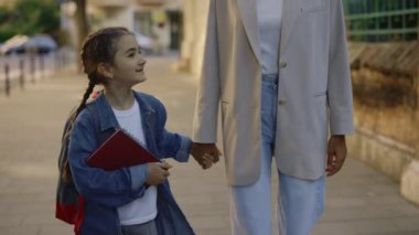 Okul sonrası ailesiyle yürürken notlarını tutan bir kız. Aile ilişkisi kavramı. Görüntüyü kapat