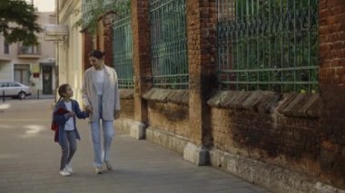 Ceketli ve kotlu güzel bir anne. Kızının elini tutuyor ve yürüyor. Okuldan dönerken küçük çocuğuyla konuşan genç bir kadın. Aile kavgası kavramı