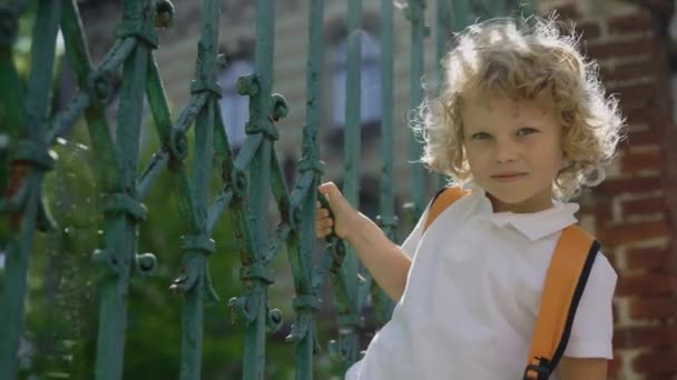 Front Side Little European Curly Boy Looking Camera Holding Gates — Vídeo de stock