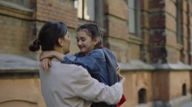 Anne çocuğuna sarıldı. Arkasını döndü ve okulun yakınındaki sokakta gözlerine baktı. Mutlu aile ve eğitim kavramı