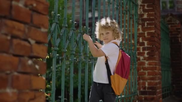 Little Schoolboy Standing Gate Playing Looking Camera Smilling School Education — Wideo stockowe