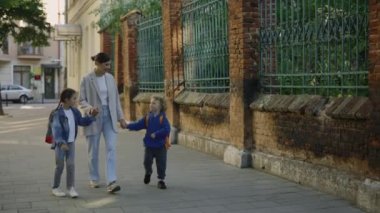 Genç bir anne sokakta çocuklarıyla konuşuyor. Kız ve erkek, annelerinin elini tutuyor ve okuldaki günlerini anlatıyor. Mutlu aile kavramı