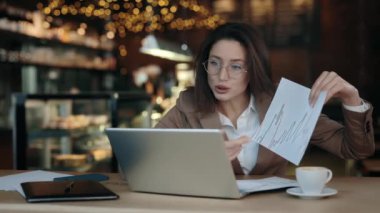 Kızgın iş kadını kafe masasında oturuyor ve video aracılığıyla ciddi bir konuşma yapıyor. Öfkeli kadın şirket hisselerinin düştüğünü gösteriyor..
