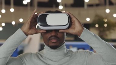 Office male worker using a VR headset, virtual reality concept. Portrait african american software developer standing in office room. It, business and new technologies concept