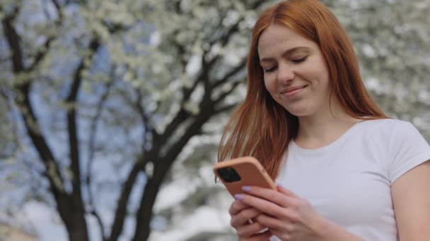 Happy Red Haired Woman Modern Smartphone Scrolling News Feed While — Stok video