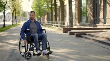 Portrait of the happy man on a wheelchair wearing casual clothes. A disabled smiled man riding in the middle of the day. People and disabled people concept