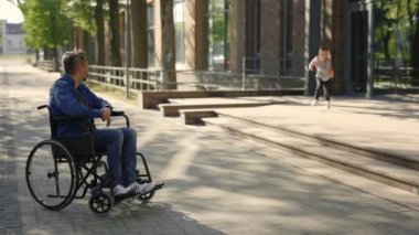 Disabled father waiting his son from the school. Happy boy pupil running from the school to take five his disabled father. Family and disabled people concept