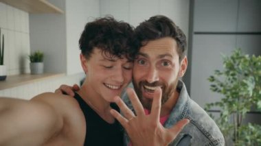 Happy lgbt gay couple doing a video call using smartphone to tell and show their friends or releatives happy news. Technology and lgbt concept