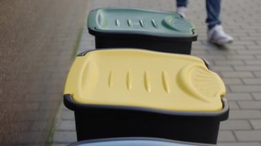 Close up of the male hands wearing special gloves puts the plastic bottle into the sorting bin got plastic. Volunteer is sorting the plastic bottles into the bins