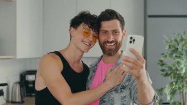 Lgbt gays smiling couple using the smartphone for video call to tell good news to their relatives or tells about their plans for future online. Technology and lgbt concept