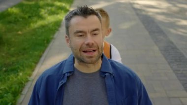 After school, the son went for a walk with his disabled father and pushes his wheelchair while telling interesting stories from school. Family and disabled people concept