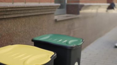 Close view of the sorting bin and the male hands in gloves puts two glass bottles inside the sorting bin. Volunteer is sorting the glass bottles into the bins