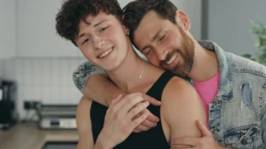 Portrait of two happy guys feeling in love with each other standing hugging in their new apartment together. People and lgbt relationship concept