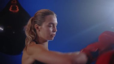 Female boxer is practicing work out boxing with personal trainer coach in the smoky boxing gym. Close up. People and boxing concept