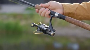 Close view of the male hands cast a fishing rod. Fathers hands shows how to use the fishing rod. People and fishing concept