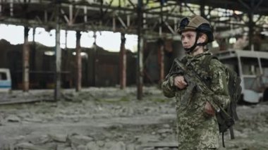 Professional female soldier with sniper rifle taking aim in destroyed industrial factory. Confident woman in uniform and helmet defending territory of ruined building.